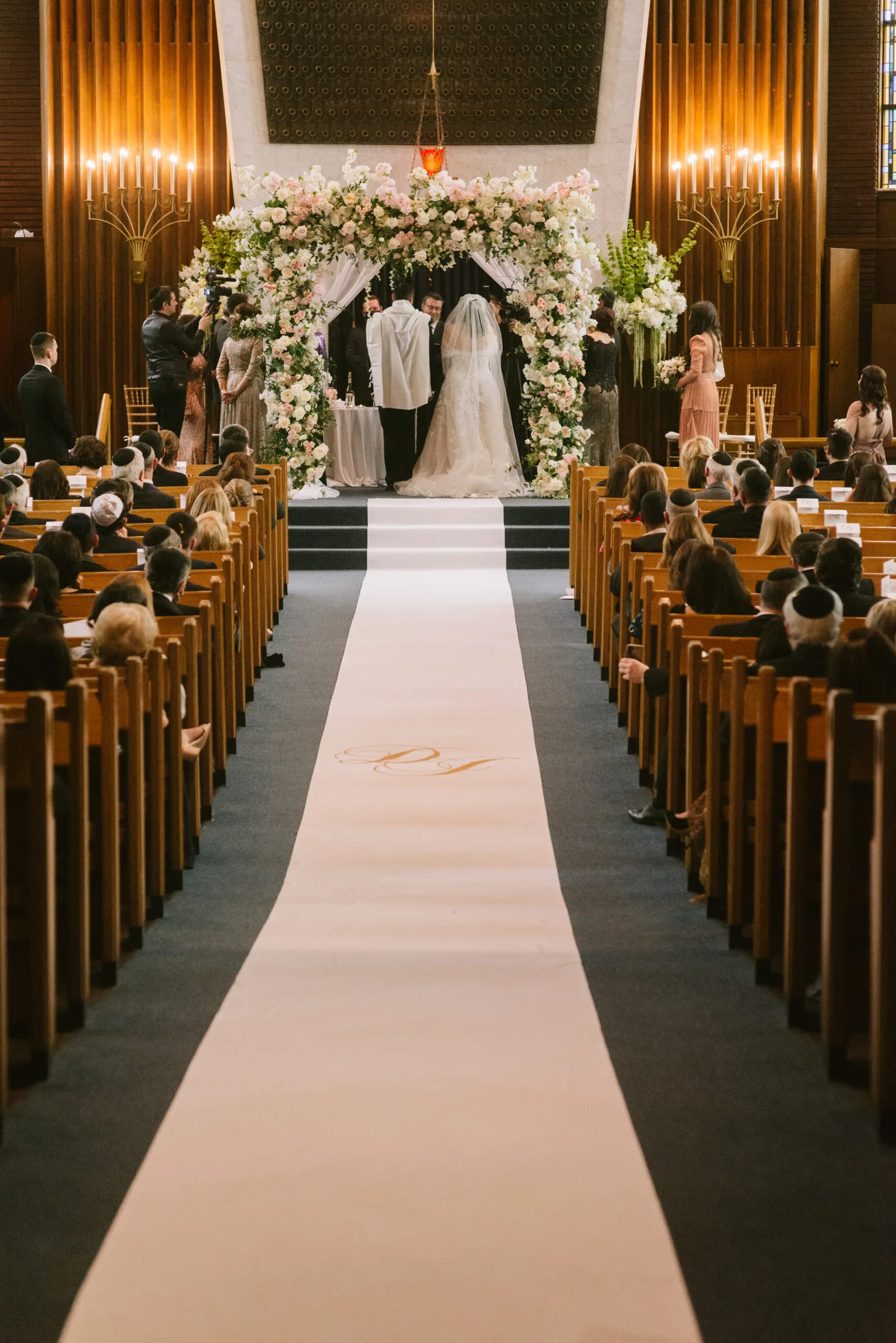 Wedding ceremony under a floral canopy at the front of a full sanctuary