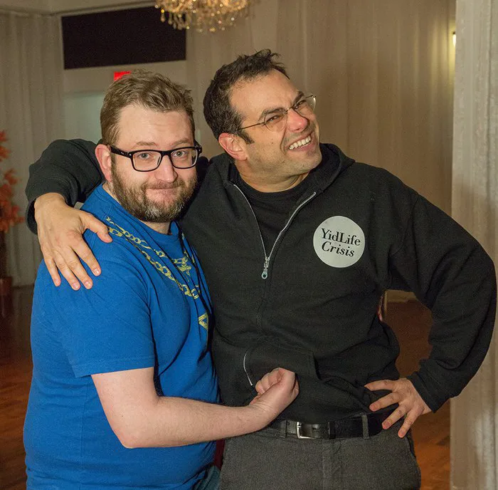 Two smiling men posing arm in arm