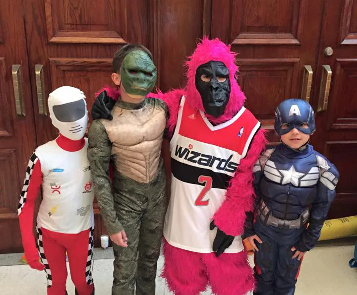 Four children in costumes, including a superhero and a pink gorilla