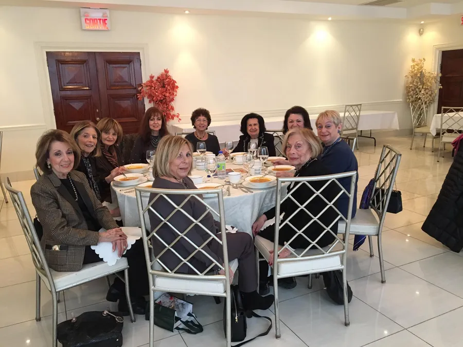 Group of women seated around a round dining table in a hall