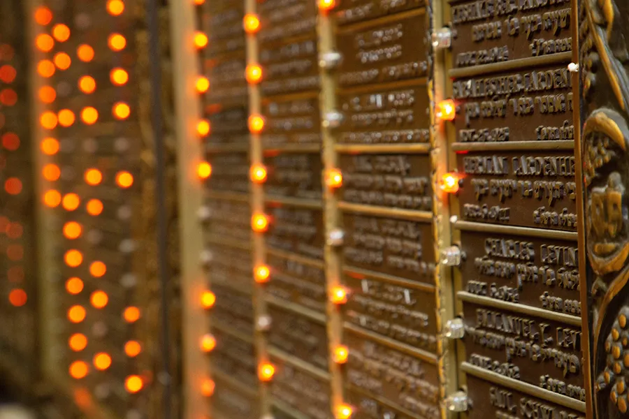 Wall of bronze memorial plaques with small lit bulbs