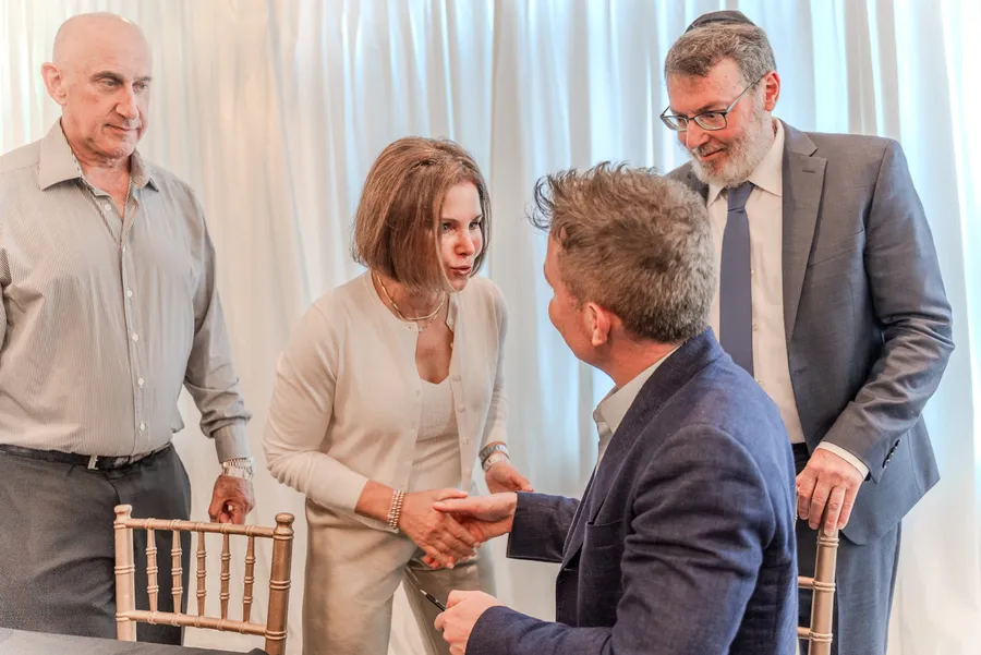 A woman shakes hands with a seated author as two men stand behind her