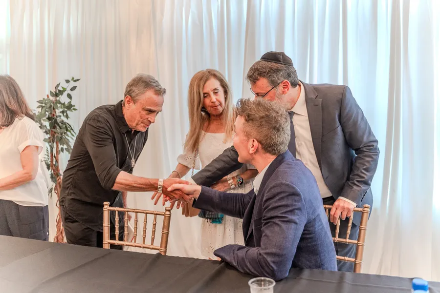 A man reaches across the signing table to shake hands with a seated author