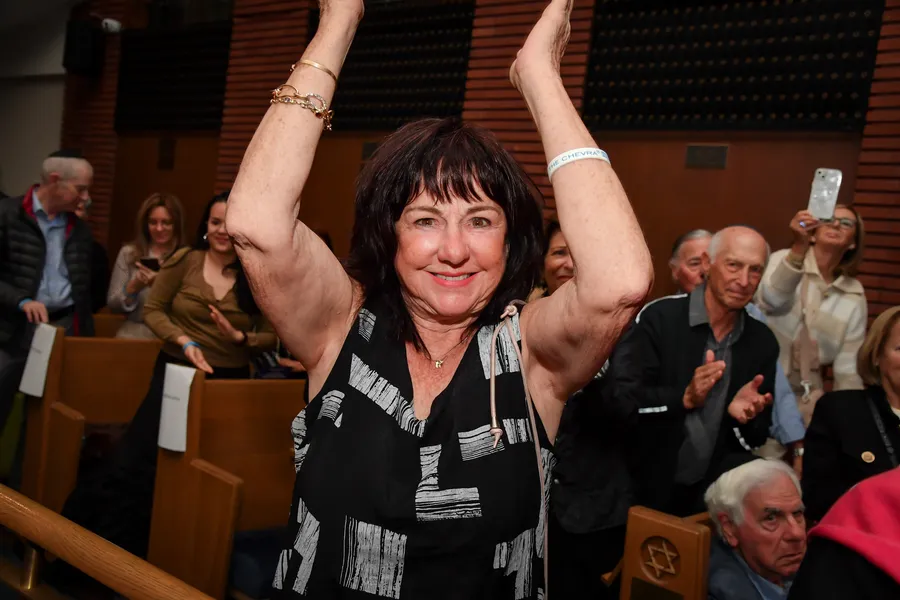 A woman with both arms raised, cheering in the pews