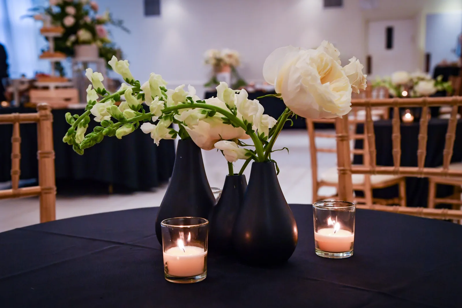 White flowers and candles on a black-clothed table