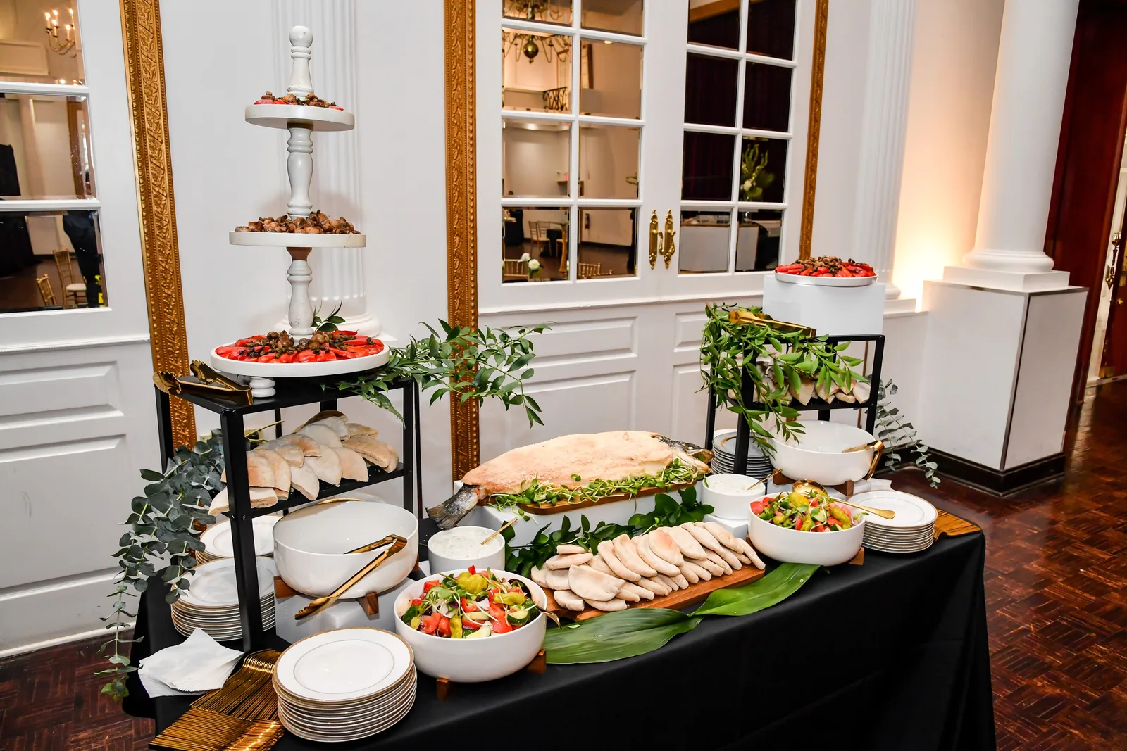 A buffet of salads and platters by the tall French windows in Singerman Hall