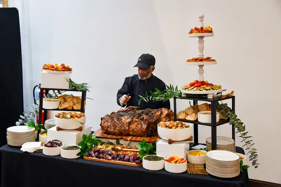 A chef at a carving station with roasts, breads and tiered platters