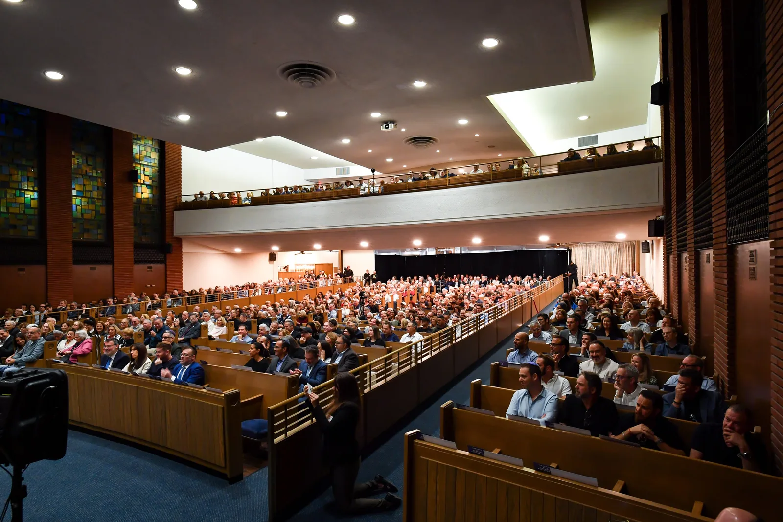 A full sanctuary, every pew and the balcony filled, under the stained-glass windows