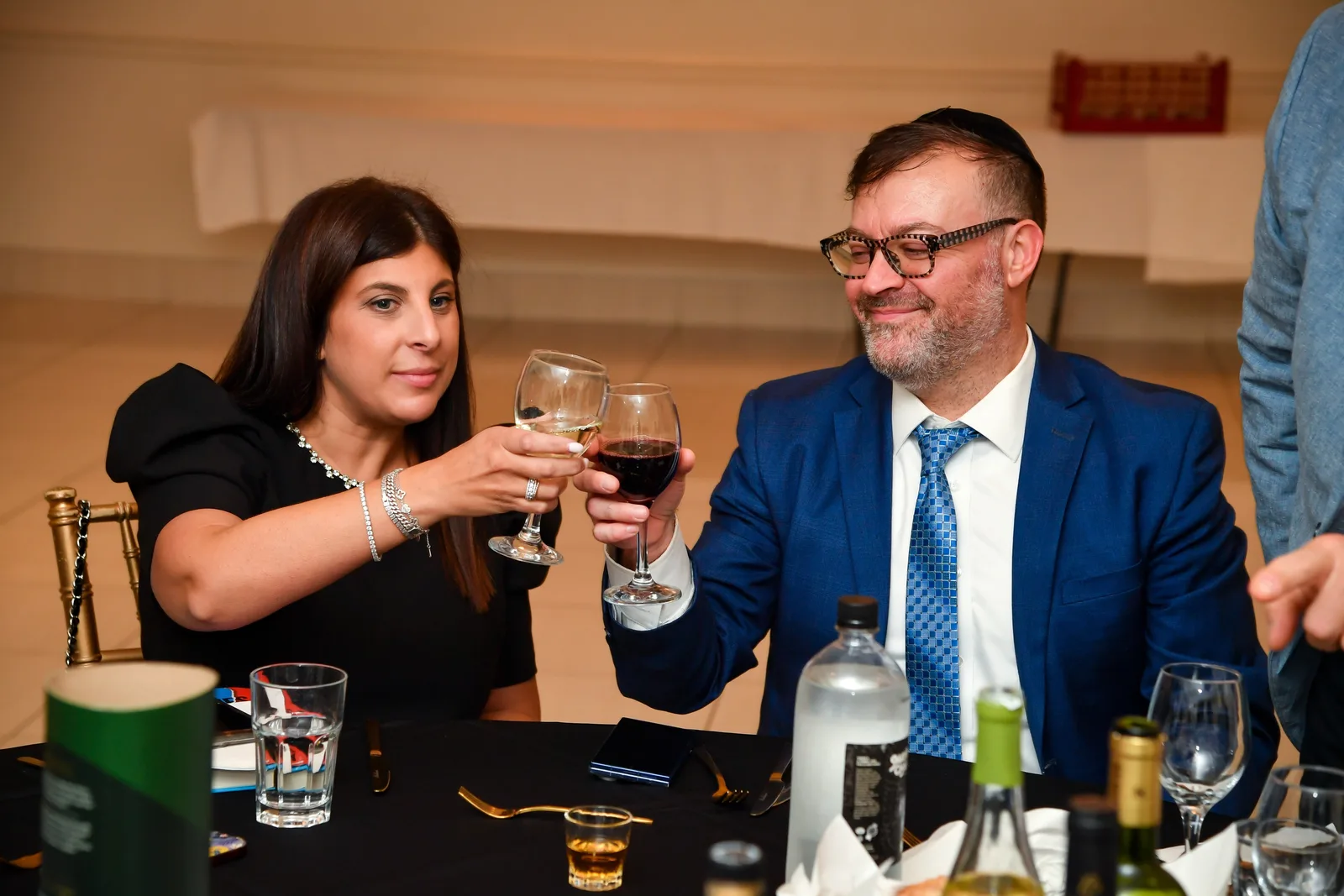 Two guests raising their glasses in a toast at dinner