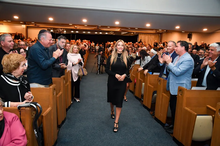 Emily Austin walks down the sanctuary aisle as the audience stands and applauds