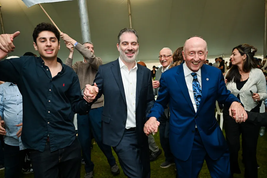 Men dancing hand in hand under the tent, beaming